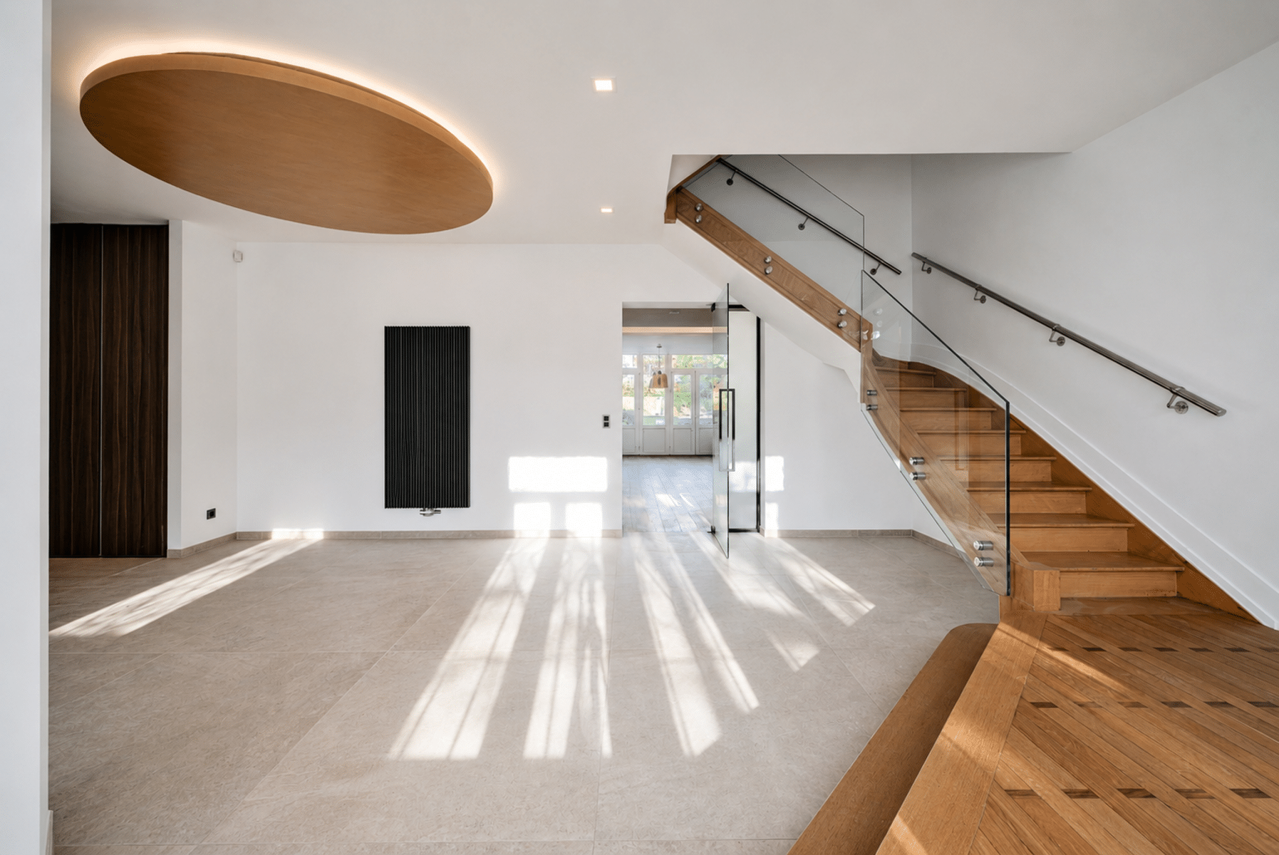 Wijze foto 10 Heldere, moderne foyer met een gebogen houten plafond en zachte achtergrondverlichting, witte muren en een grote glazen trap aan de rechterkant.