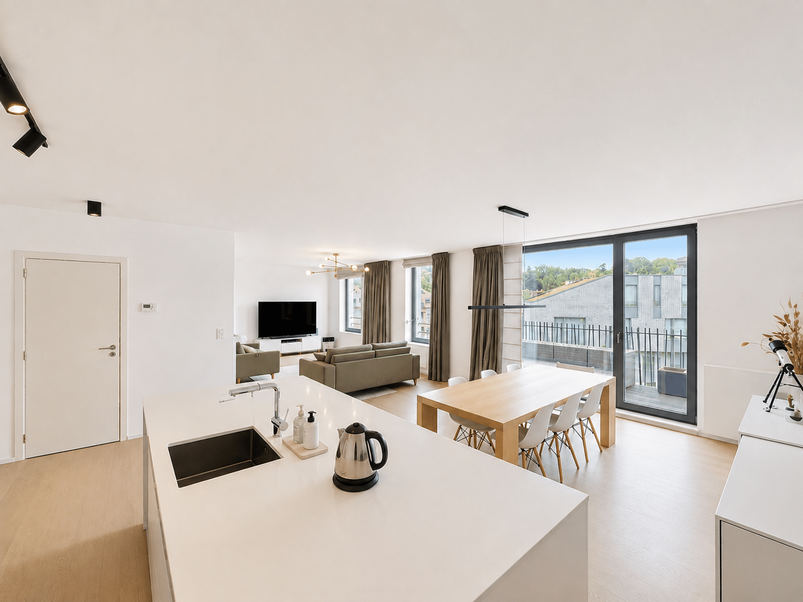 Séjour Lumineux avec Cuisine Ouverte – You Real Estate Agency Appartement moderne avec cuisine ouverte, salon lumineux et balcon.
