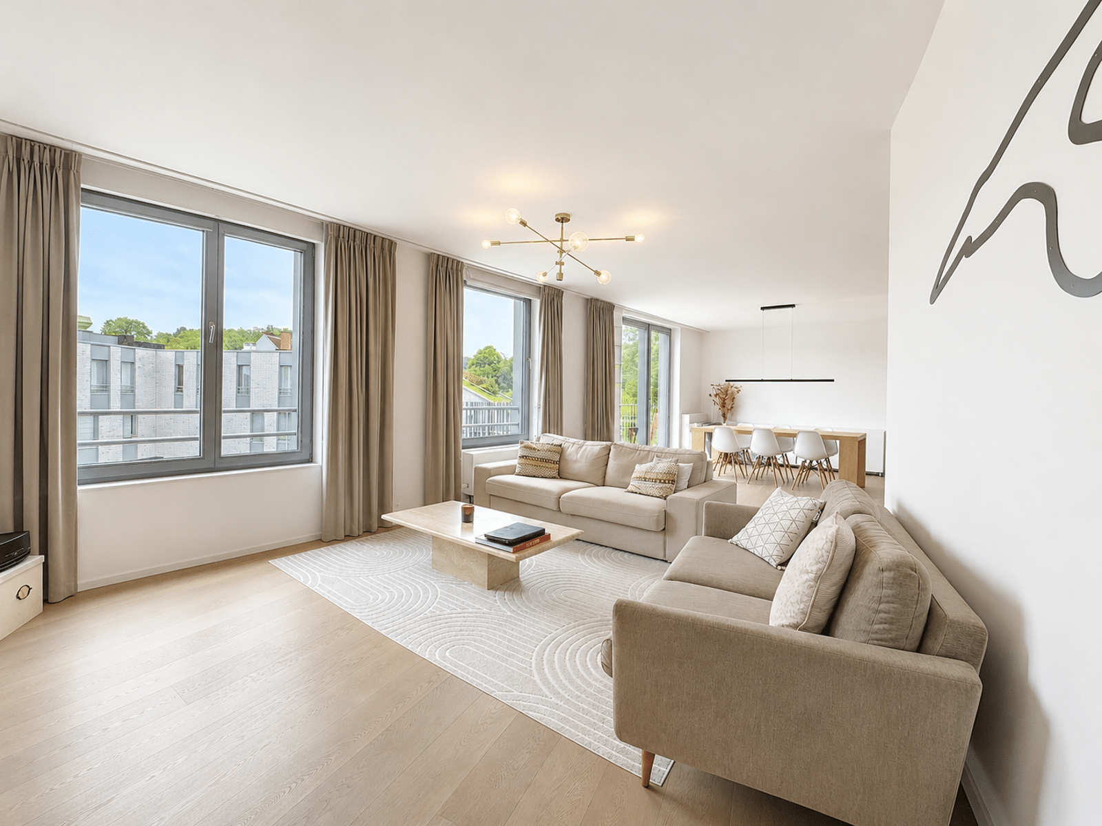 Salon et Salle à Manger Lumineux – You Real Estate Agency Salon et salle à manger lumineux dans appartement moderne avec grandes fenêtres.