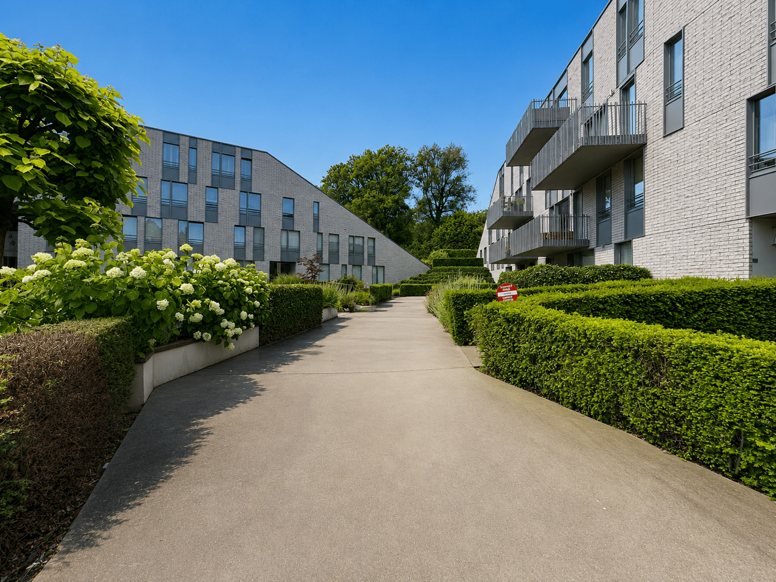Cour Intérieure Résidentielle Paysagée – You Real Estate Agency Cour intérieure paysagée d’une résidence moderne avec appartements et balcons.
