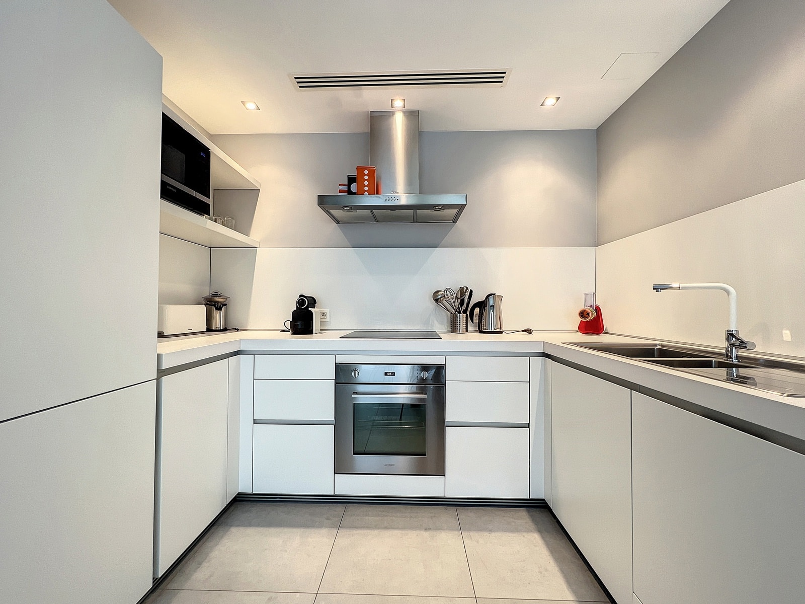 whise photo 3 Modern minimalist L-shaped kitchen with white cabinets, built-in oven, stovetop, and stainless steel range hood.
