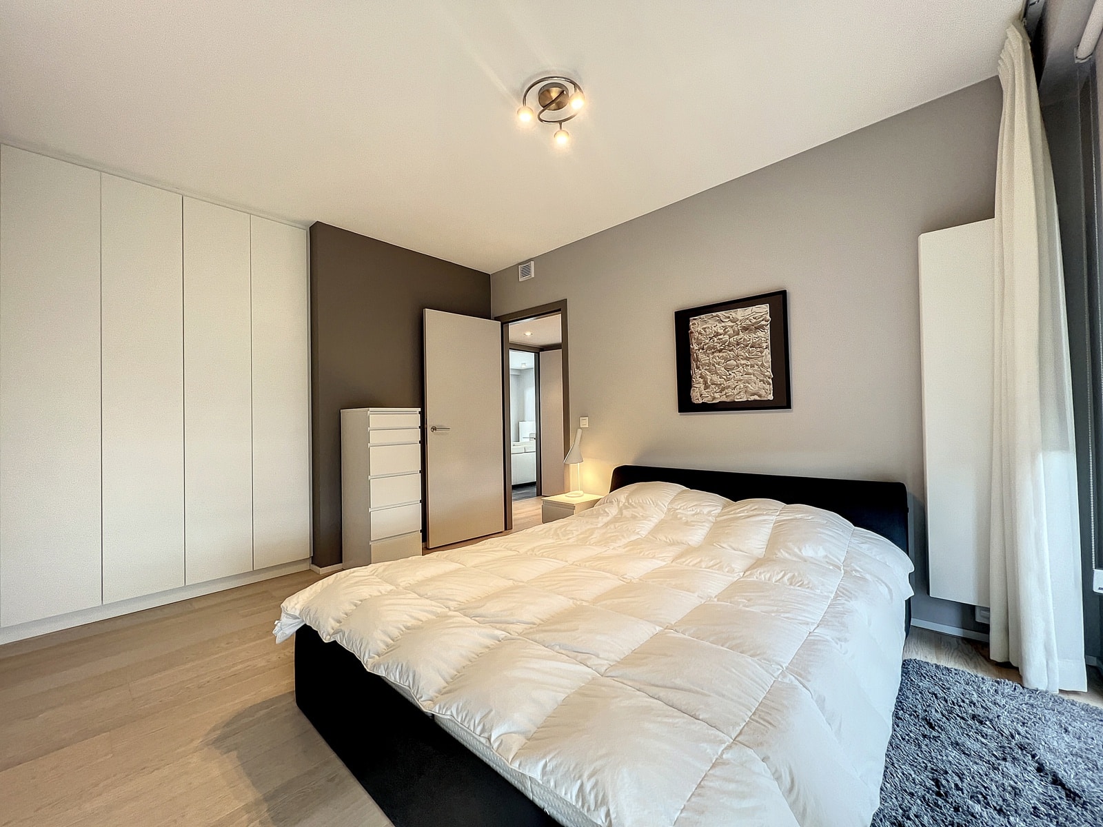 whise photo 8 Modern bedroom with white built-in wardrobes, gray accent wall, and a low black bed with a white duvet.