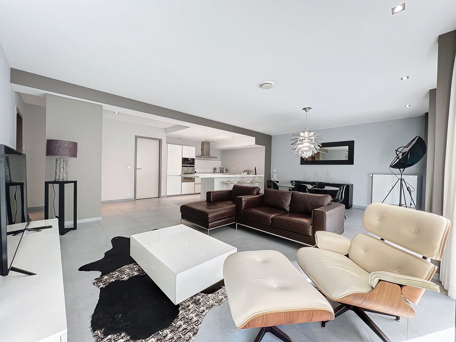 Salon Moderne avec Cuisine Ouverte – You Real Estate Agency Appartement moderne avec salon lumineux, cuisine ouverte et espace repas design.