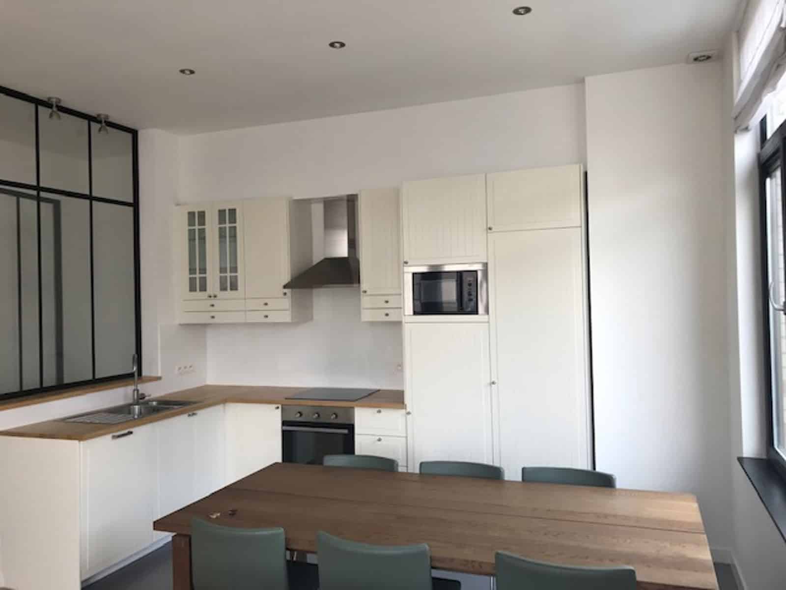 whise photo 4 Bright modern kitchen with white cabinetry, wooden countertops, built-in oven, microwave, and a large wooden dining table.