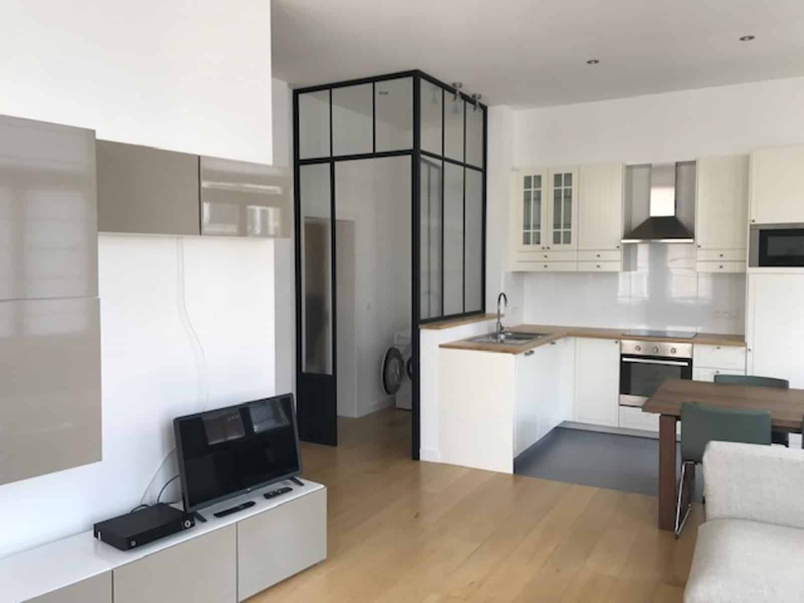 Séjour Ouvert avec Cuisine Équipée – You Real Estate Agency Appartement moderne avec salon ouvert, cuisine équipée et cloison verrière.