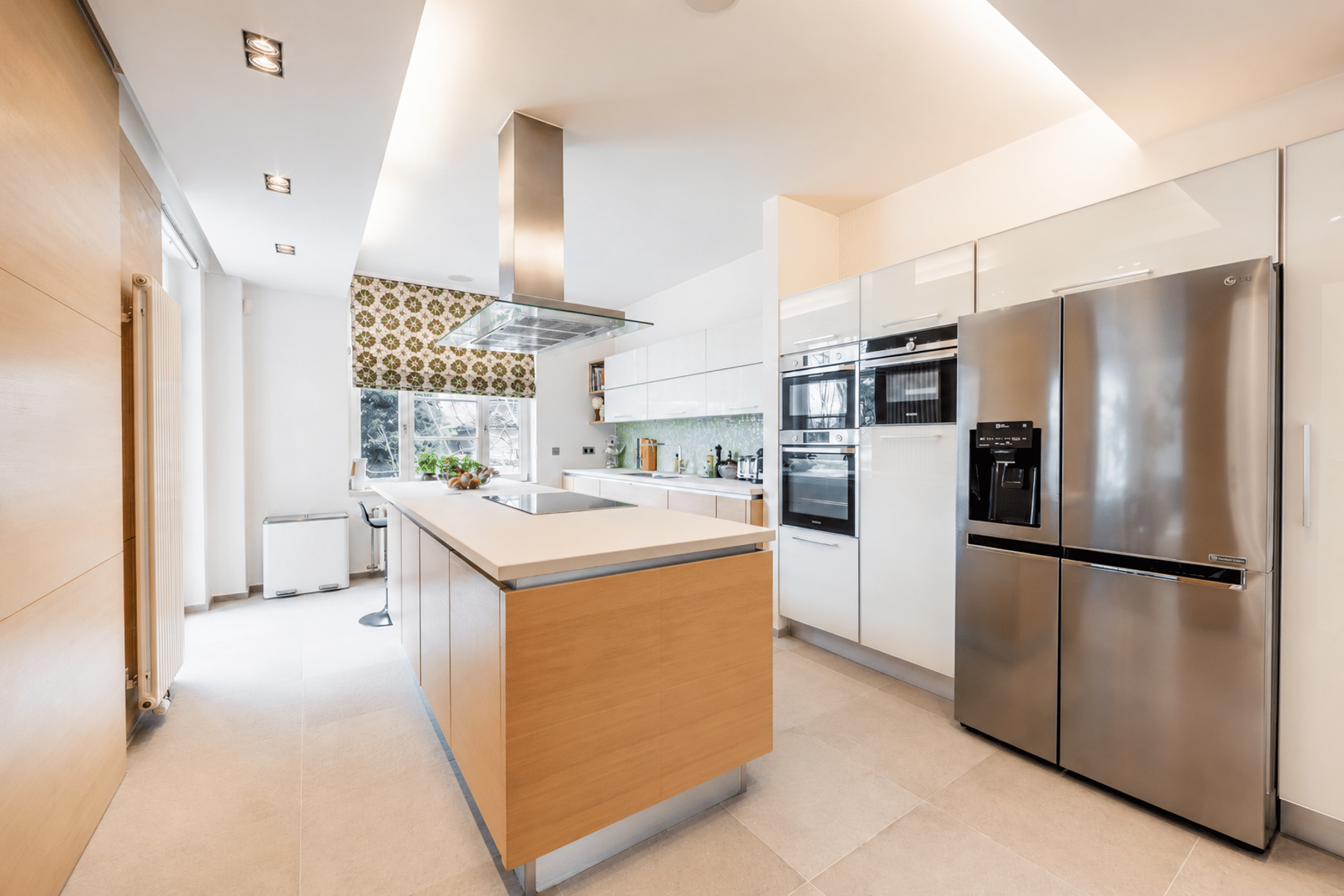 whise photo 10 Modern kitchen with a central wooden island, stainless steel fridge and double ovens along white glossy cabinets.