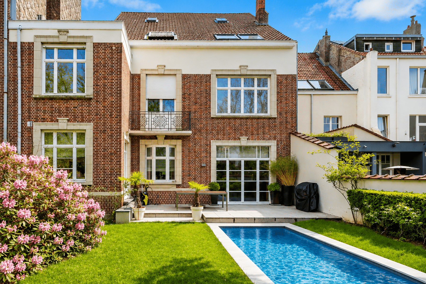 whise photo 11 Backyard of a brick townhouse featuring a rectangular blue pool, green lawn, potted plants, and pink flowering shrub in bloom