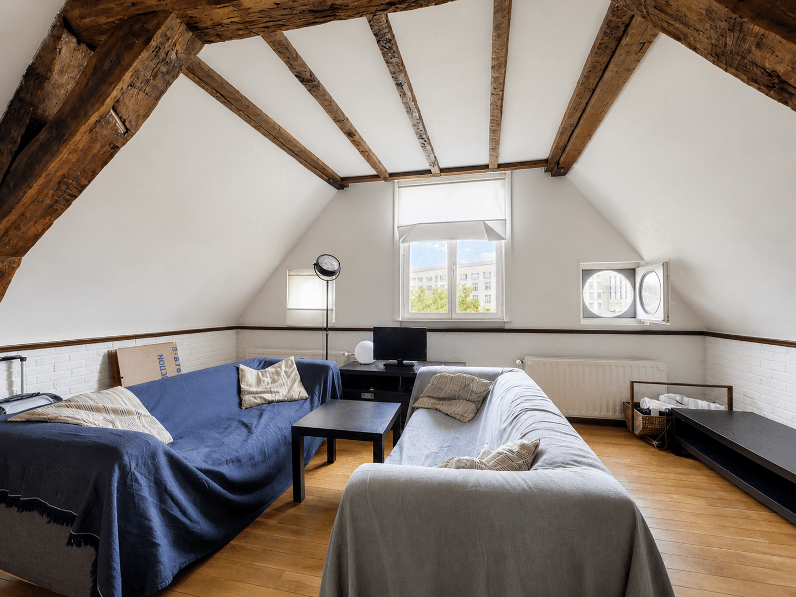 whise photo 3 Attic living room with exposed dark wooden beams, two sofas, and a small coffee table.
