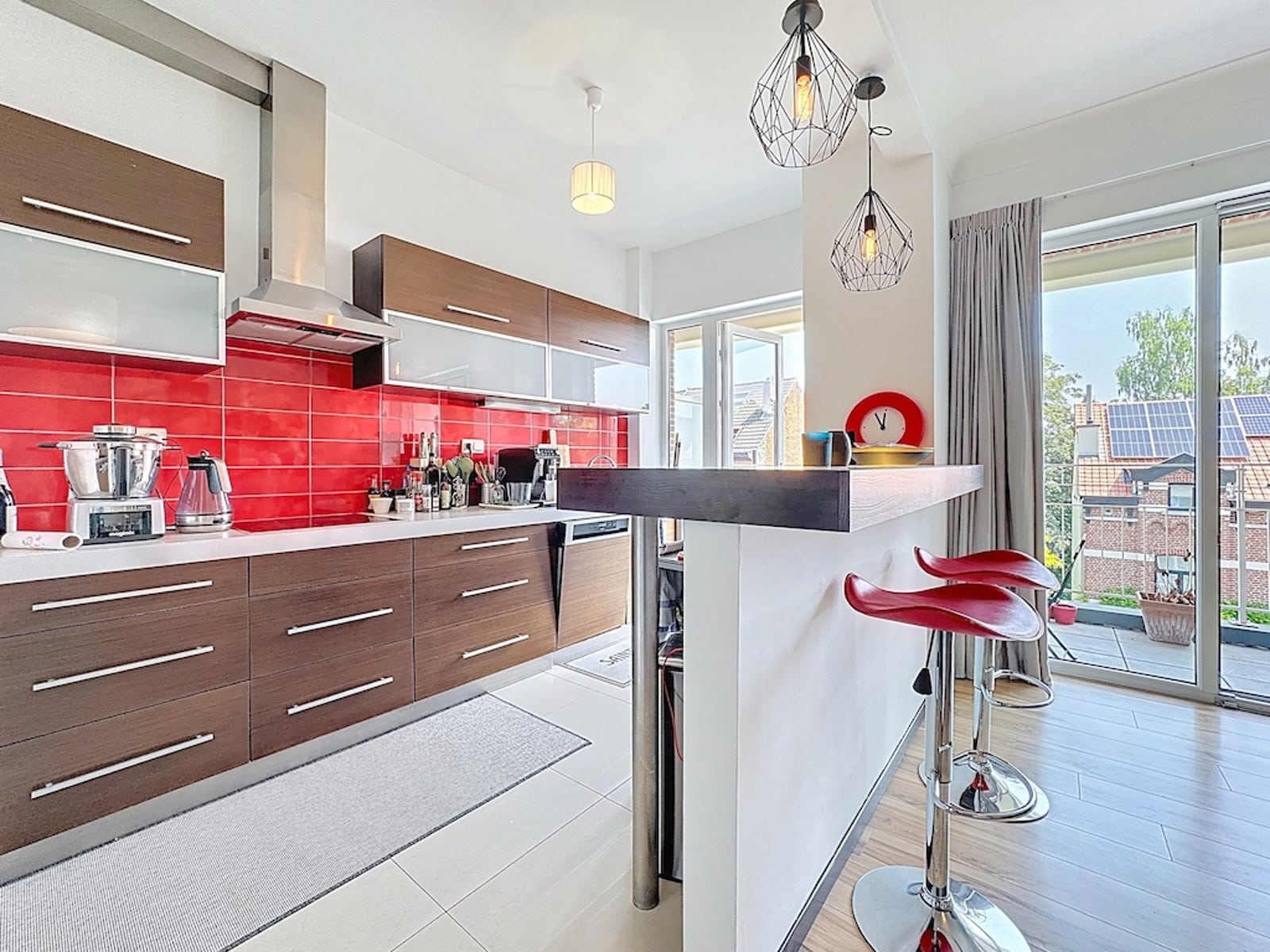 Modern Kitchen with a Red Backsplash – You Real Estate Agency Modern apartment kitchen with a red backsplash and a bright terrace.