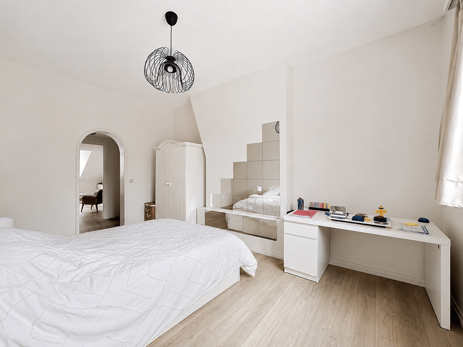 whise photo 3 Bright minimalist bedroom with white furniture, a quilted white bed, a white desk with books, and a black geometric pendant light overhead.