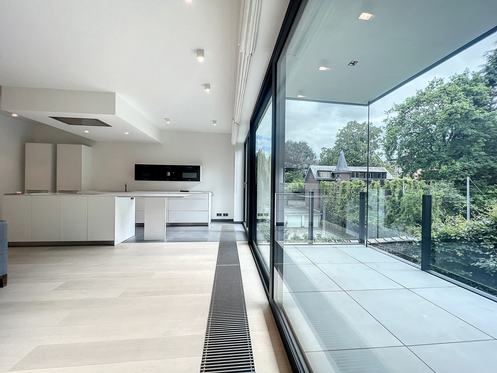 Cuisine Ouverte avec Terrasse – You Real Estate Agency Appartement moderne avec cuisine ouverte, salon lumineux et terrasse vitrée.