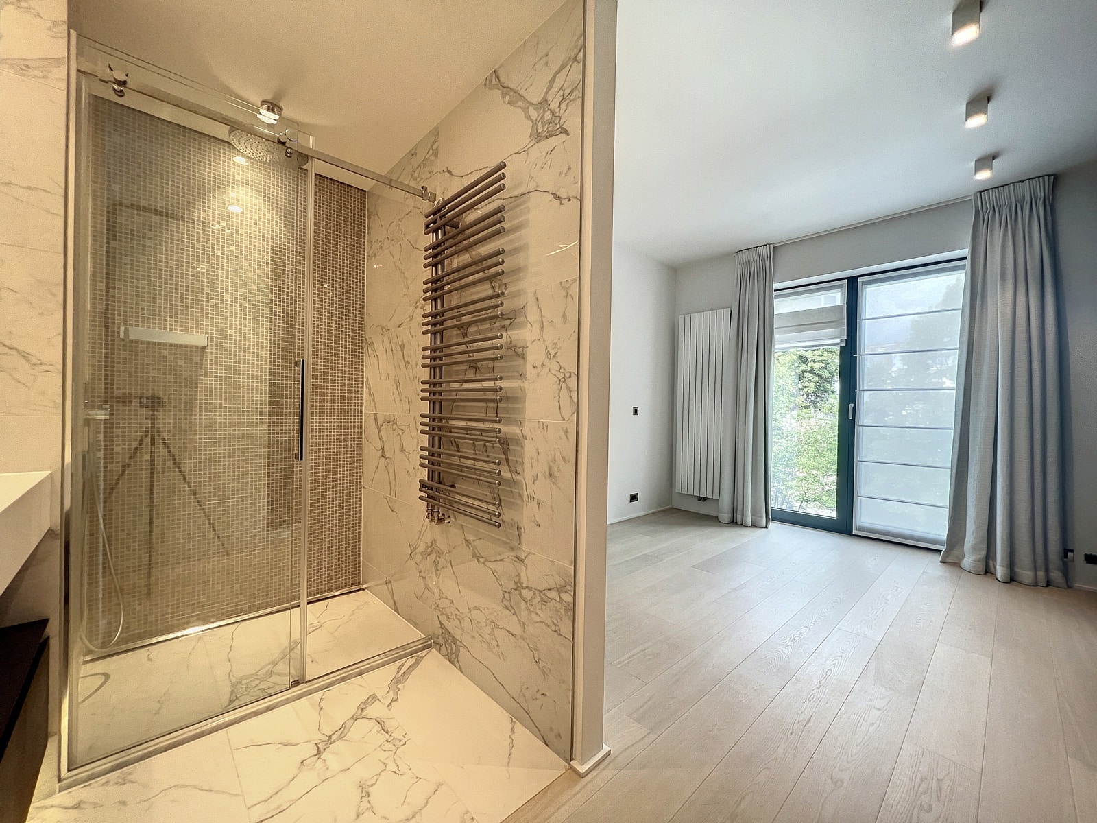 Salle de Bain et Chambre Lumineuse – You Real Estate Agency Salle de bain moderne avec douche à l’italienne et chambre lumineuse en appartement.