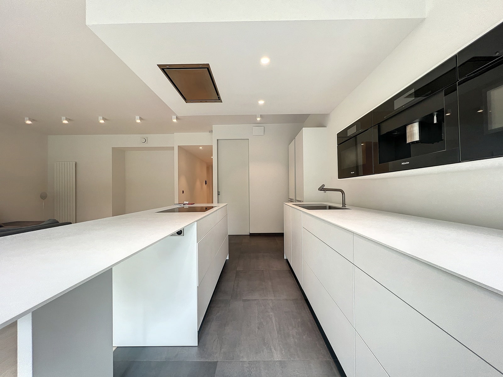 whise photo 5 Modern white kitchen with parallel island counters, induction cooktop, and sink, featuring integrated appliances in a minimalist style.