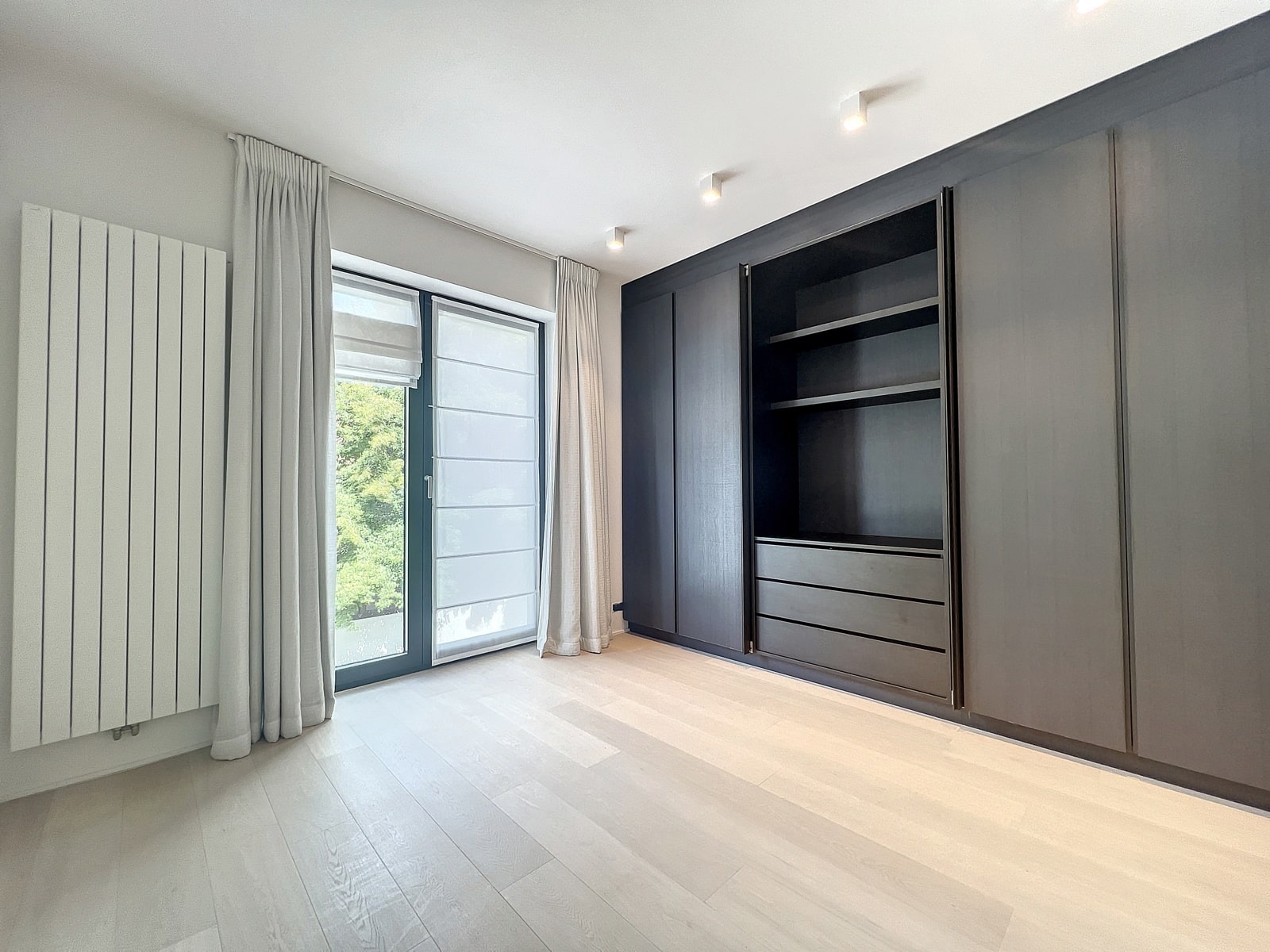 Chambre Moderne avec Dressing Intégré – You Real Estate Agency Chambre moderne avec dressing intégré, parquet clair et grande fenêtre en appartement.