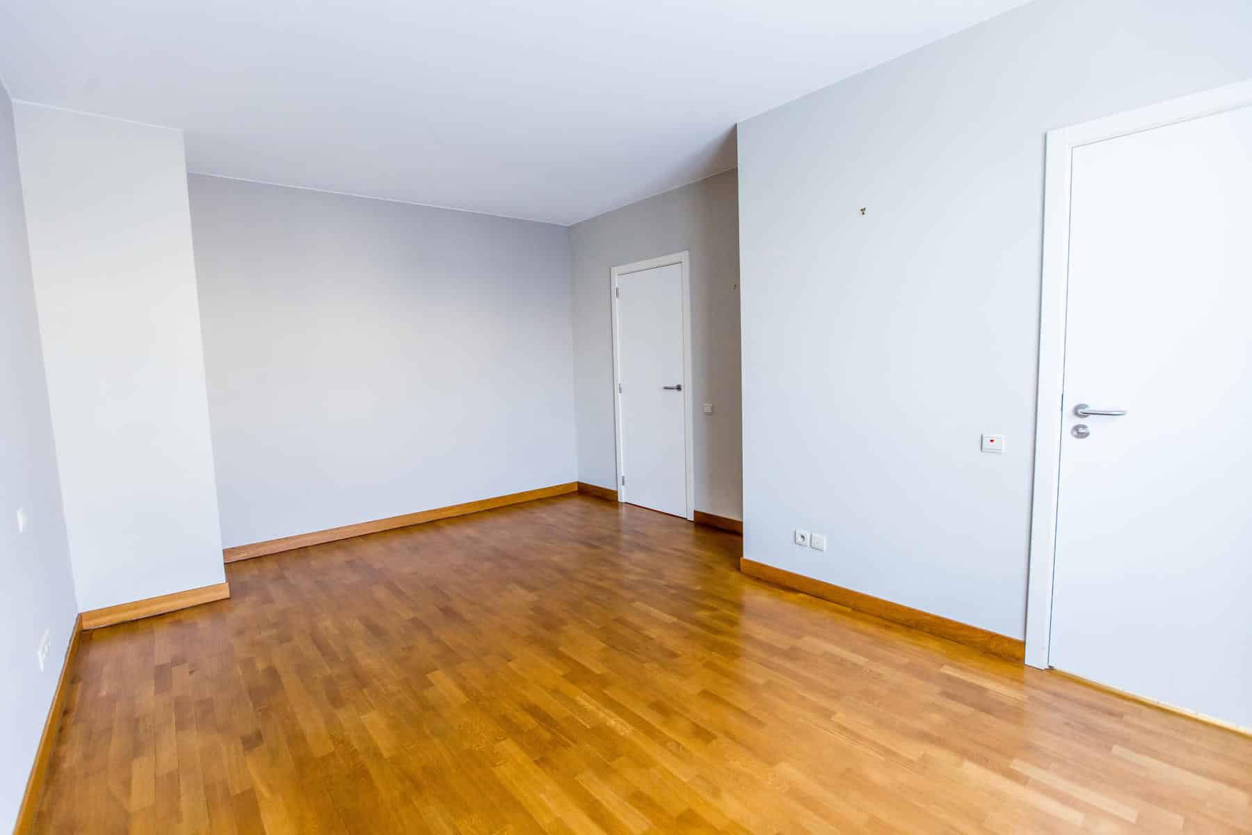 whise photo 7 Empty room with light-gray walls, wooden floor, and white doors along one wall; minimal and unoccupied.