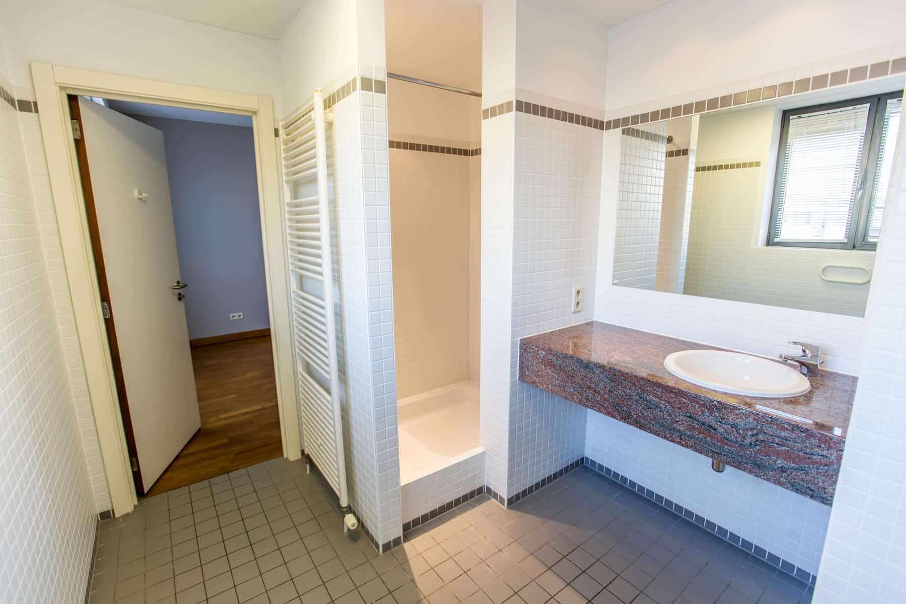 whise photo 9 Bathroom with a marble countertop sink, large mirror, window, and tiled shower area