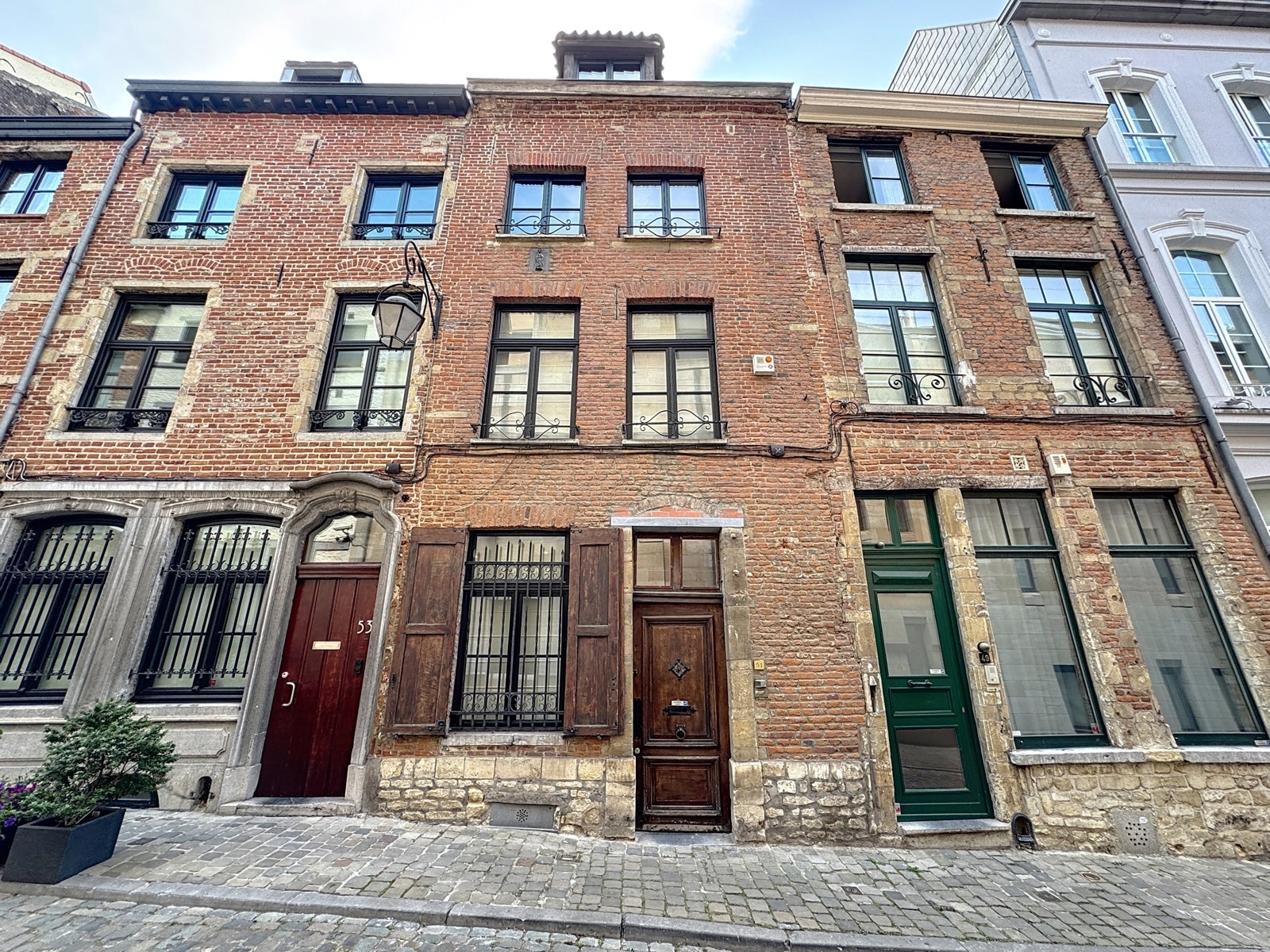 Maisons de Ville Historiques – You Real Estate Agency Maisons de ville en brique sur rue pavée, façade historique.