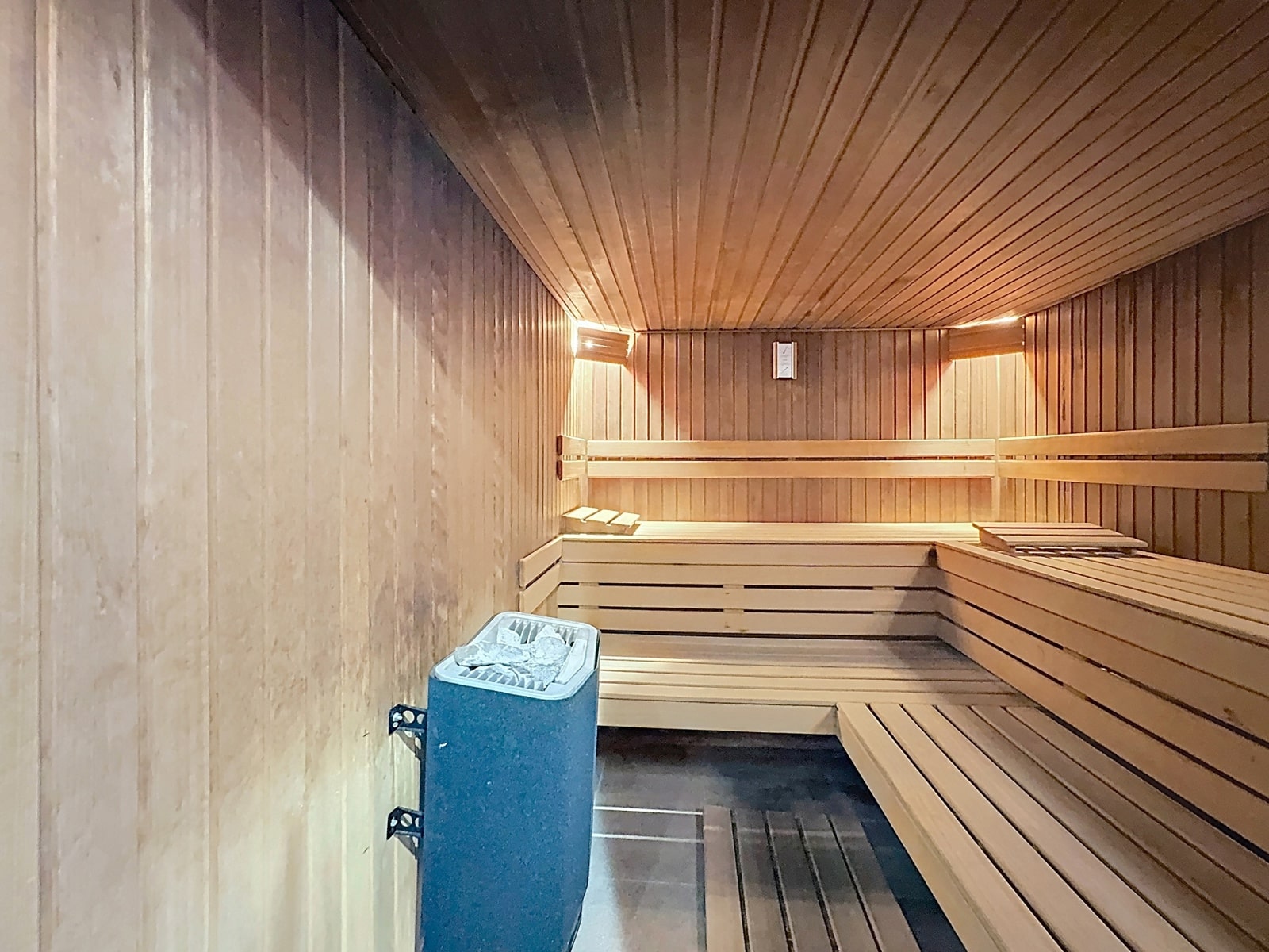 Wijze foto 10 Inside a wooden sauna with tiered benches along the walls and a heater at the front center-right.