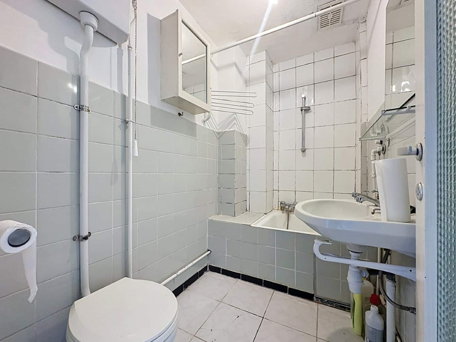 whise photo 4 Small white-tiled bathroom with toilet, sink, bathtub, and exposed pipes