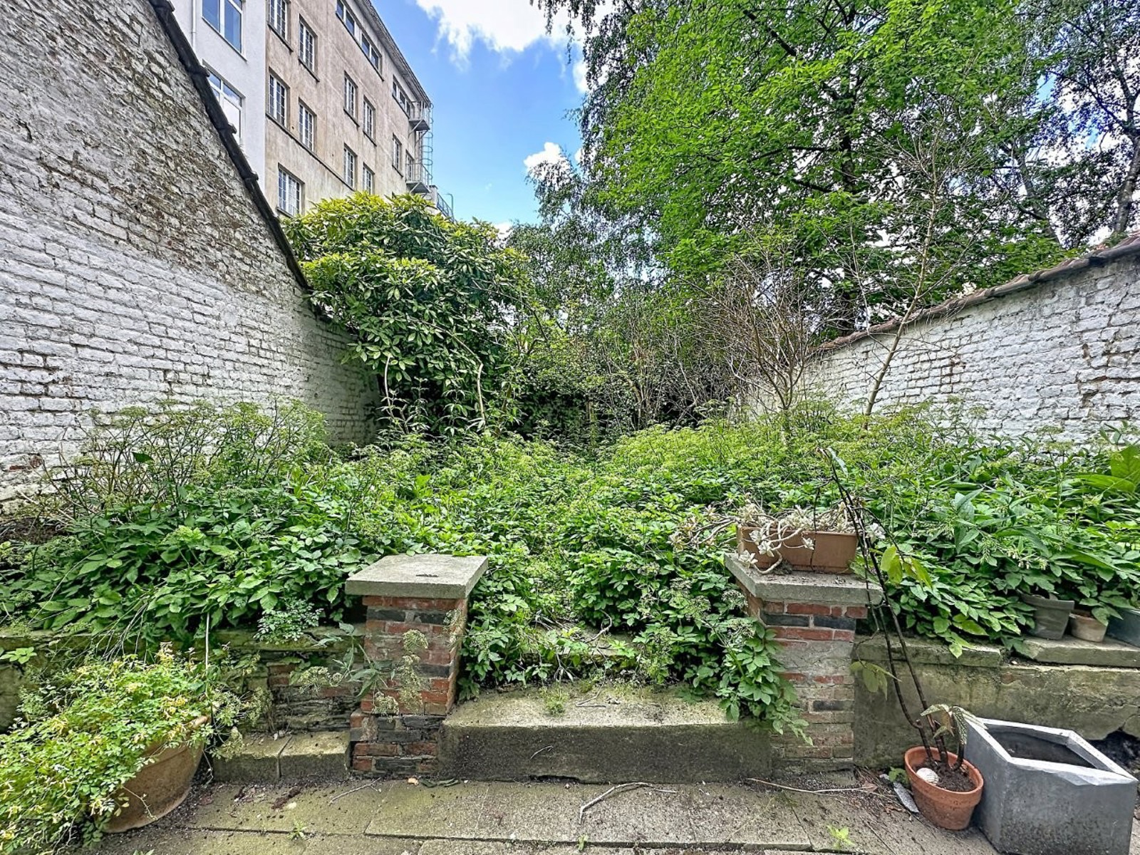 Terrasse Avec Jardin Urbain – You Real Estate Agency Terrasse avec jardin urbain verdoyant et murs en briques blanches pour appartement.