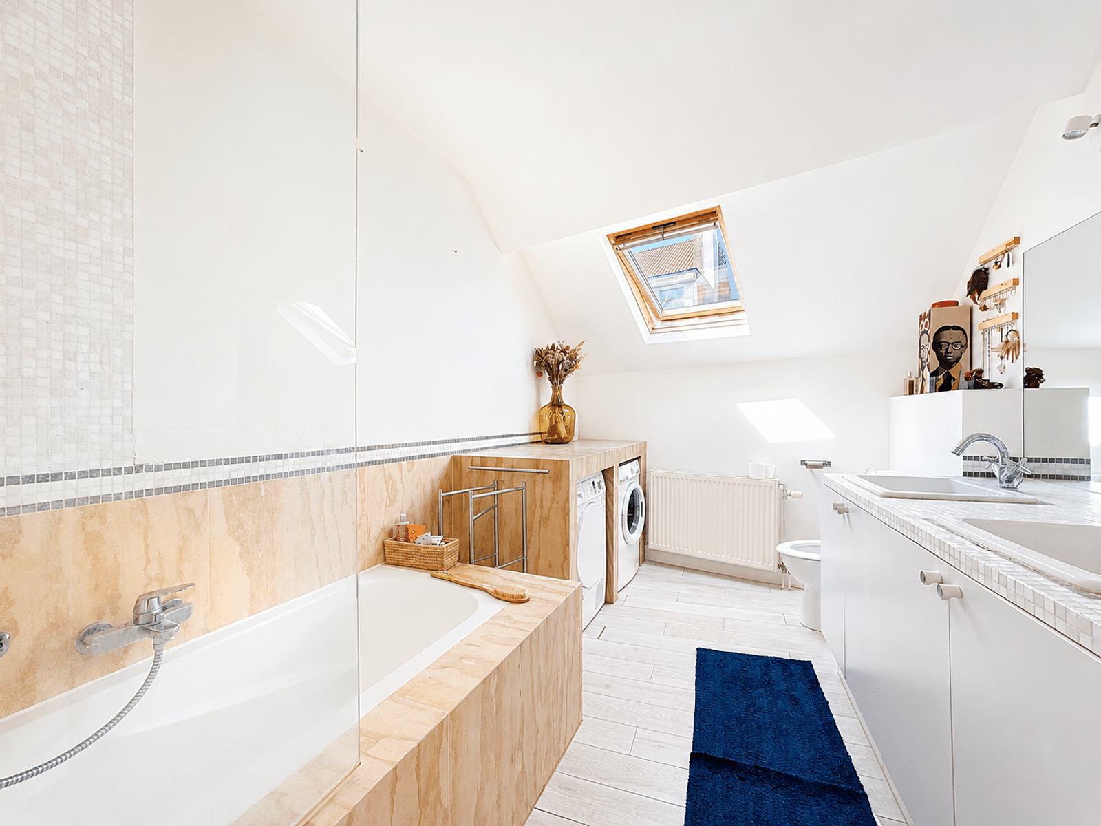 Salle de Bains Mansardée Lumineuse – You Real Estate Agency Salle de bains mansardée lumineuse avec baignoire et double vasque en appartement.