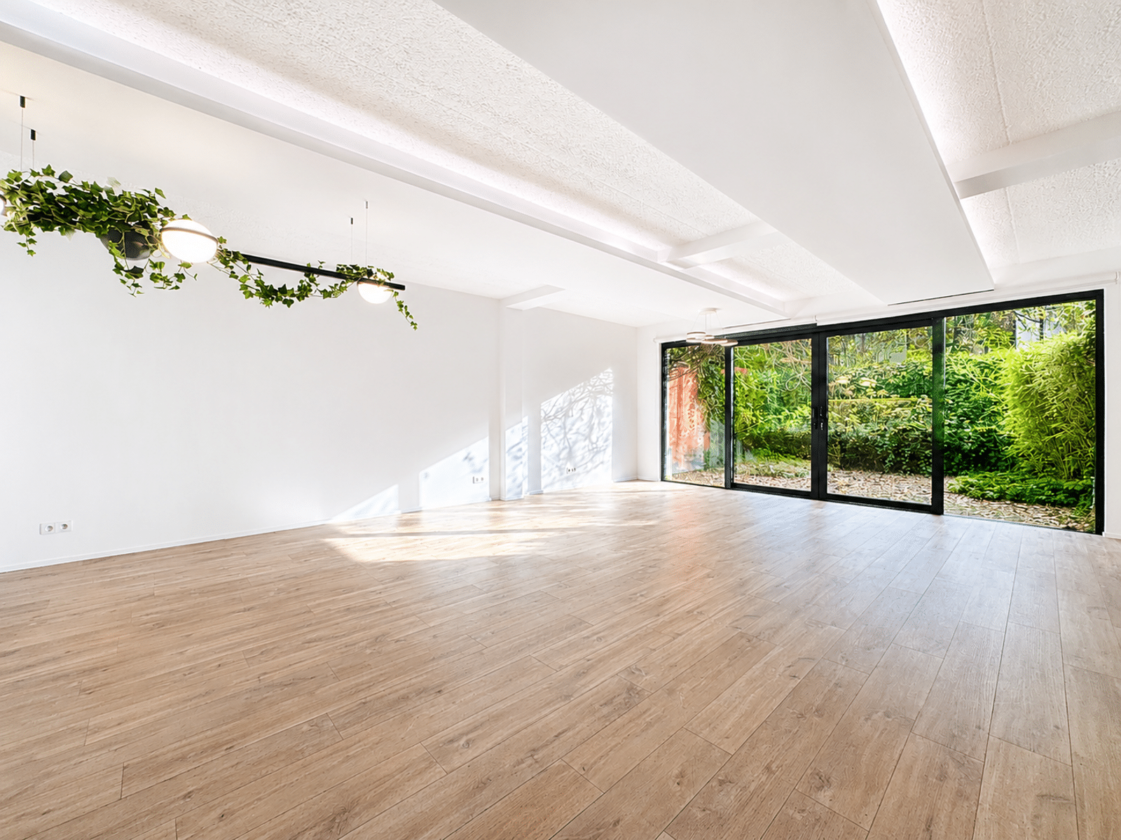 Salon Lumineux avec Vue sur Jardin – You Real Estate Agency Salon moderne lumineux avec parquet, baies vitrées et vue sur jardin.