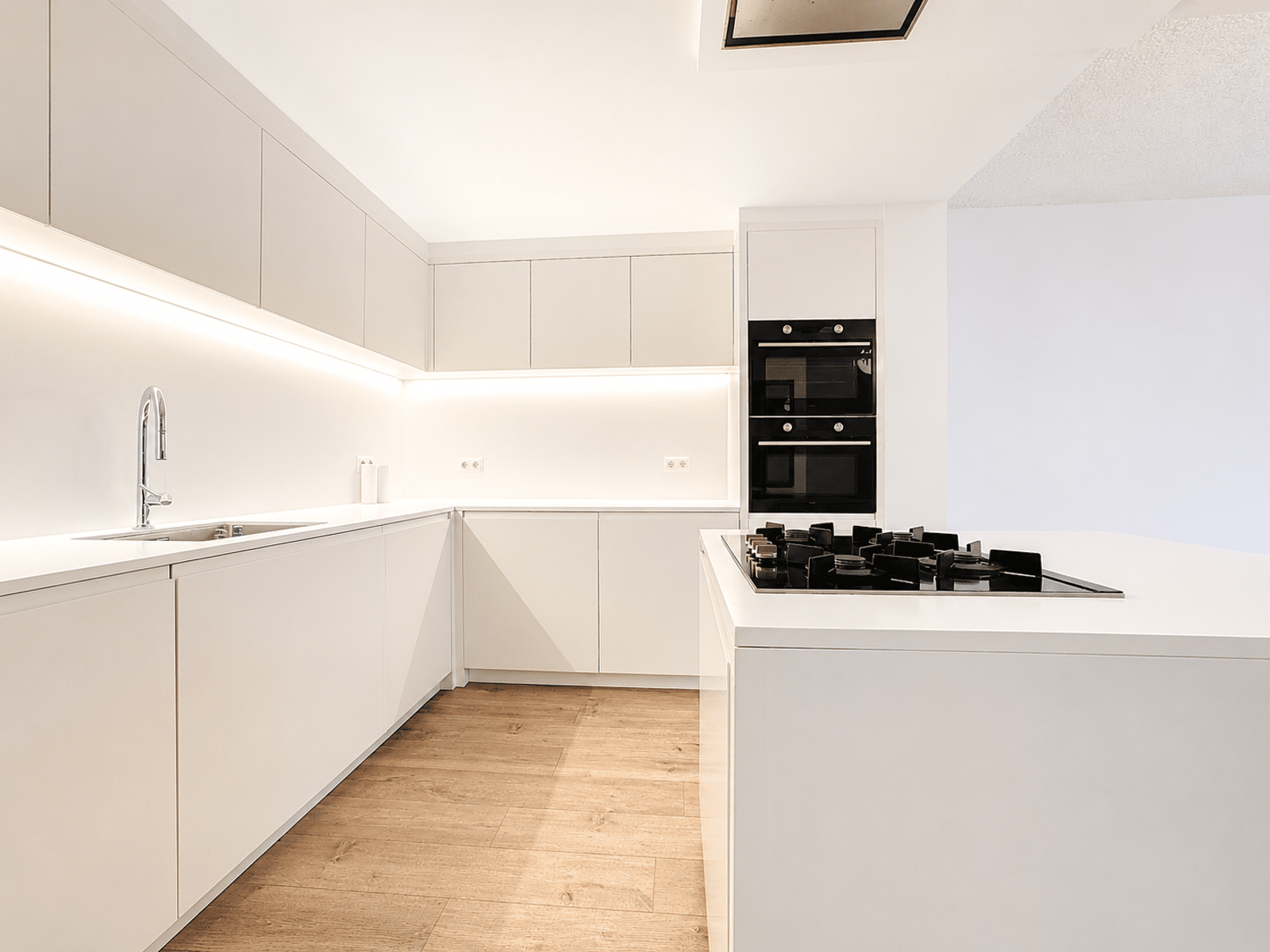 Cuisine Moderne avec Îlot – You Real Estate Agency Cuisine équipée moderne avec îlot, fours encastrés et parquet clair.