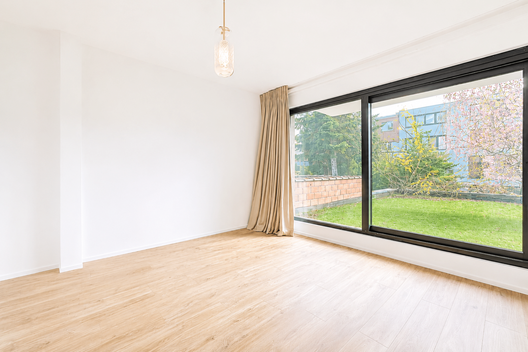 Pièce Lumineuse avec Vue sur Jardin – You Real Estate Agency Pièce lumineuse avec parquet, grande baie vitrée et vue jardin dans maison moderne.