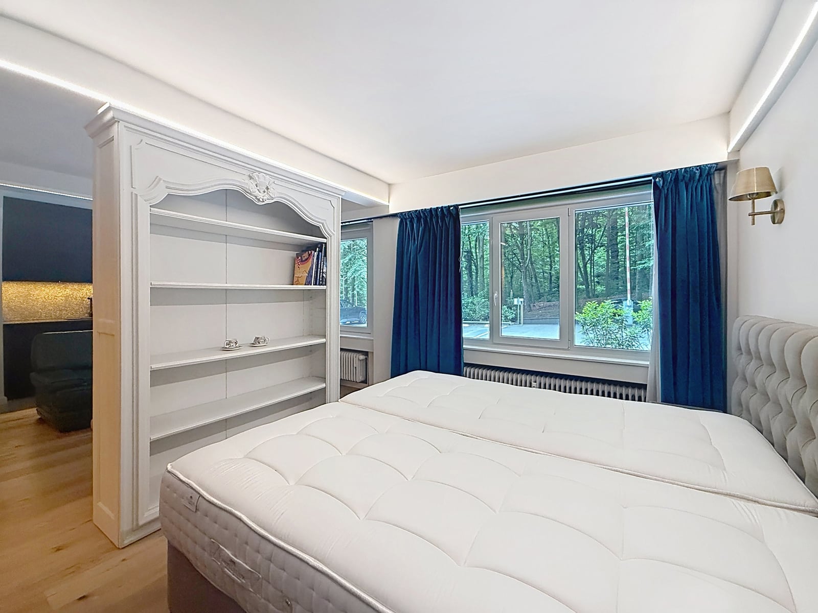 Lichte kamer met uitzicht op de bomen – You Real Estate Agency Lichte slaapkamer in een appartement met twee eenpersoonsbedden, een groot raam en uitzicht op de bomen.