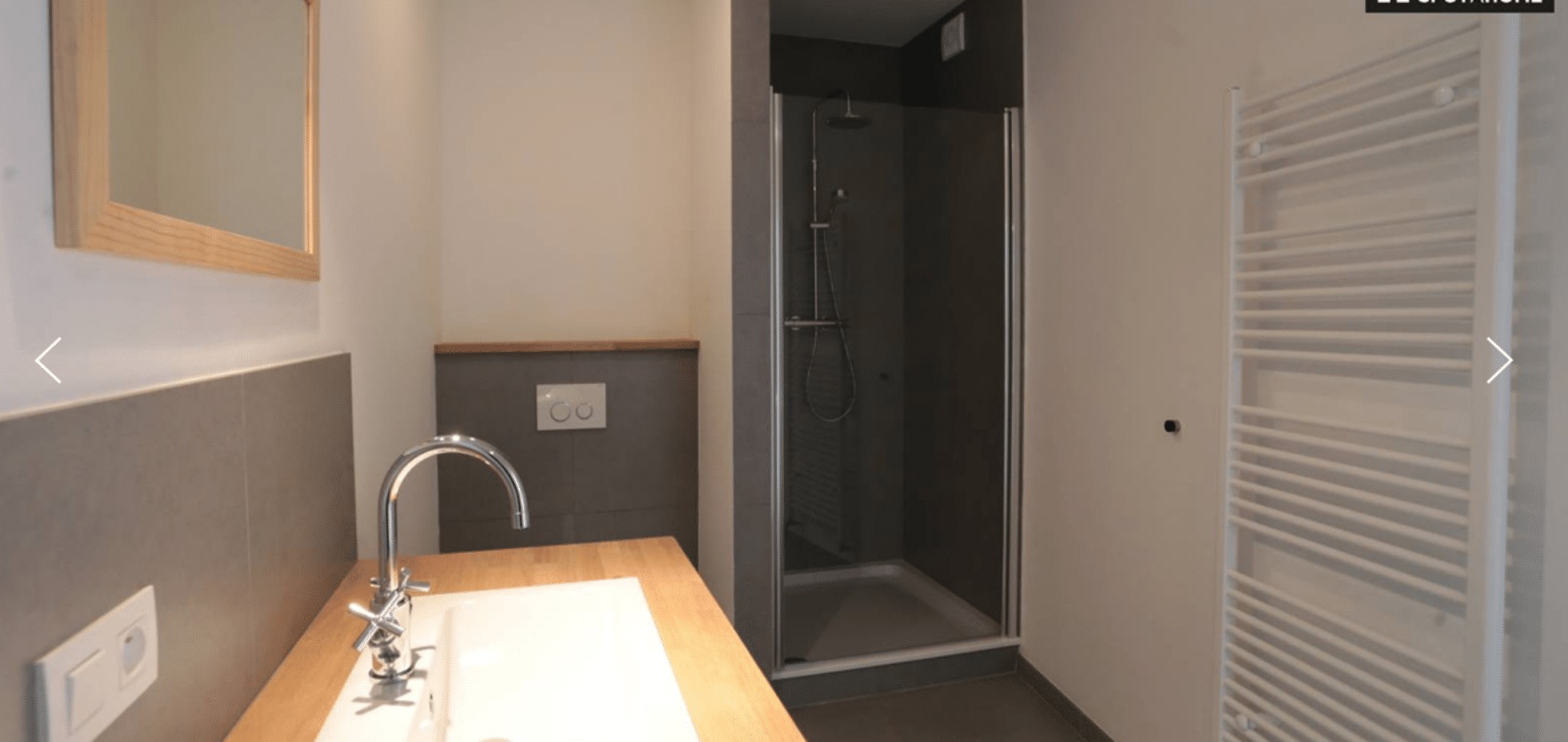 Salle de Bain avec Douche Vitrée – You Real Estate Agency Salle de bain moderne d’appartement avec douche vitrée et meuble vasque en bois.