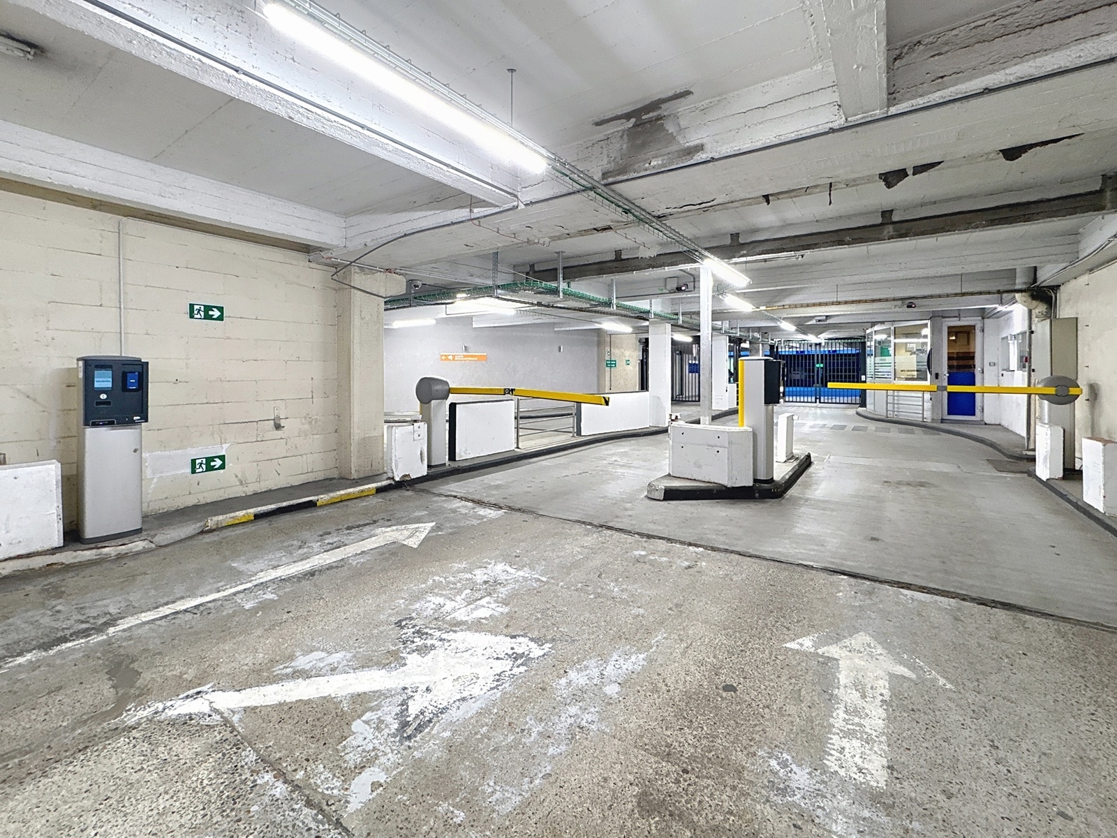 Parking Intérieur Sécurisé – You Real Estate Agency Parking intérieur sécurisé d’un immeuble avec barrières d’accès automatisées.