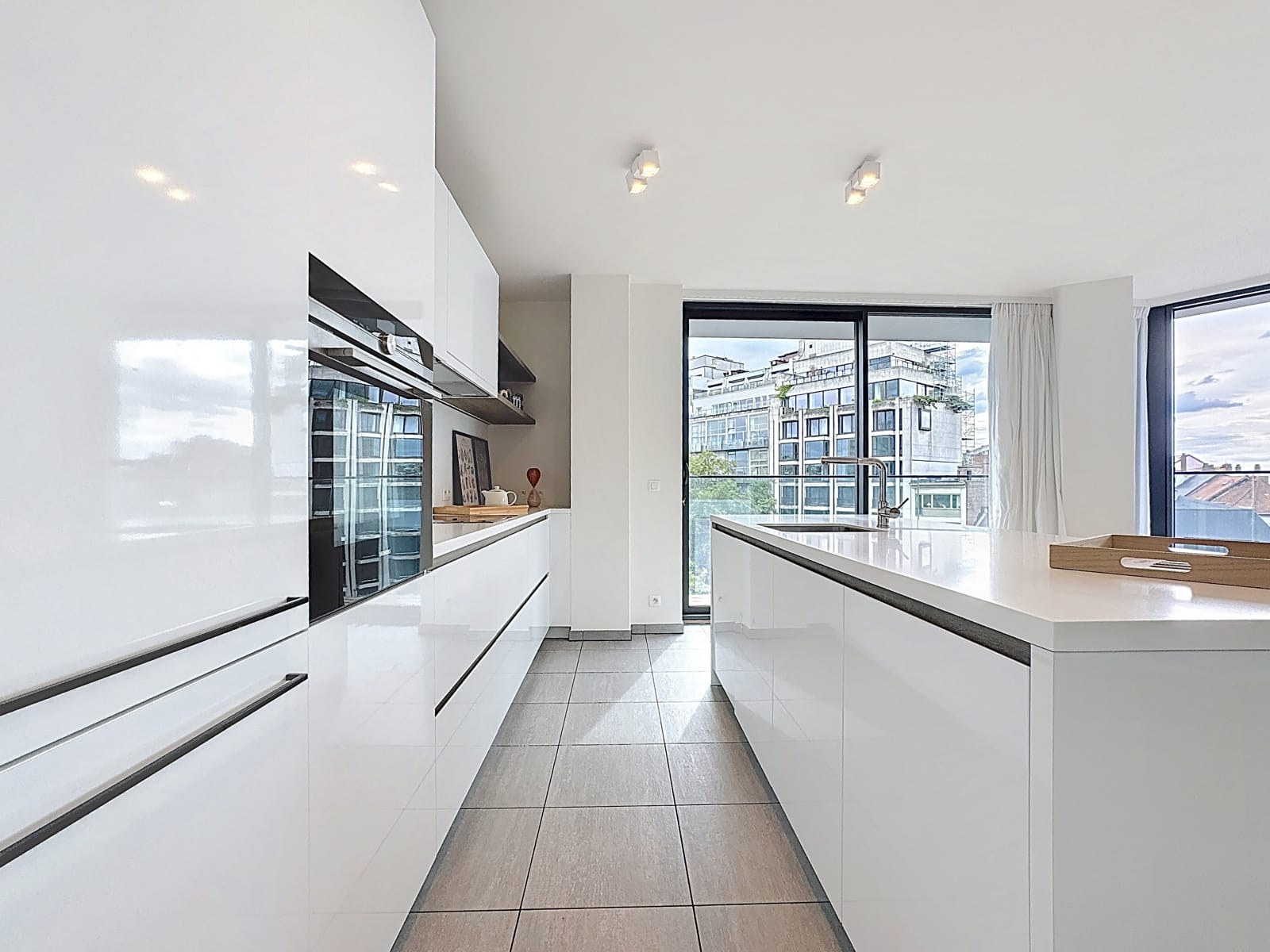 Cuisine Moderne Avec Îlot Central – You Real Estate Agency Cuisine moderne blanche avec îlot central et grandes fenêtres dans un appartement lumineux.