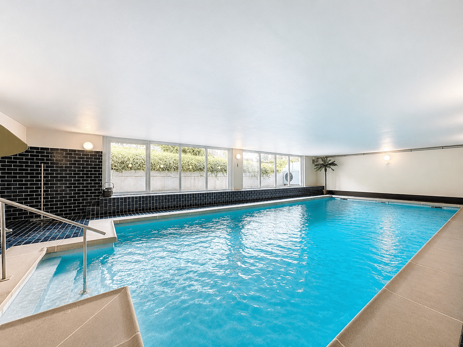 Piscine Intérieure Moderne – You Real Estate Agency Piscine intérieure moderne avec grandes baies vitrées dans une maison de standing.