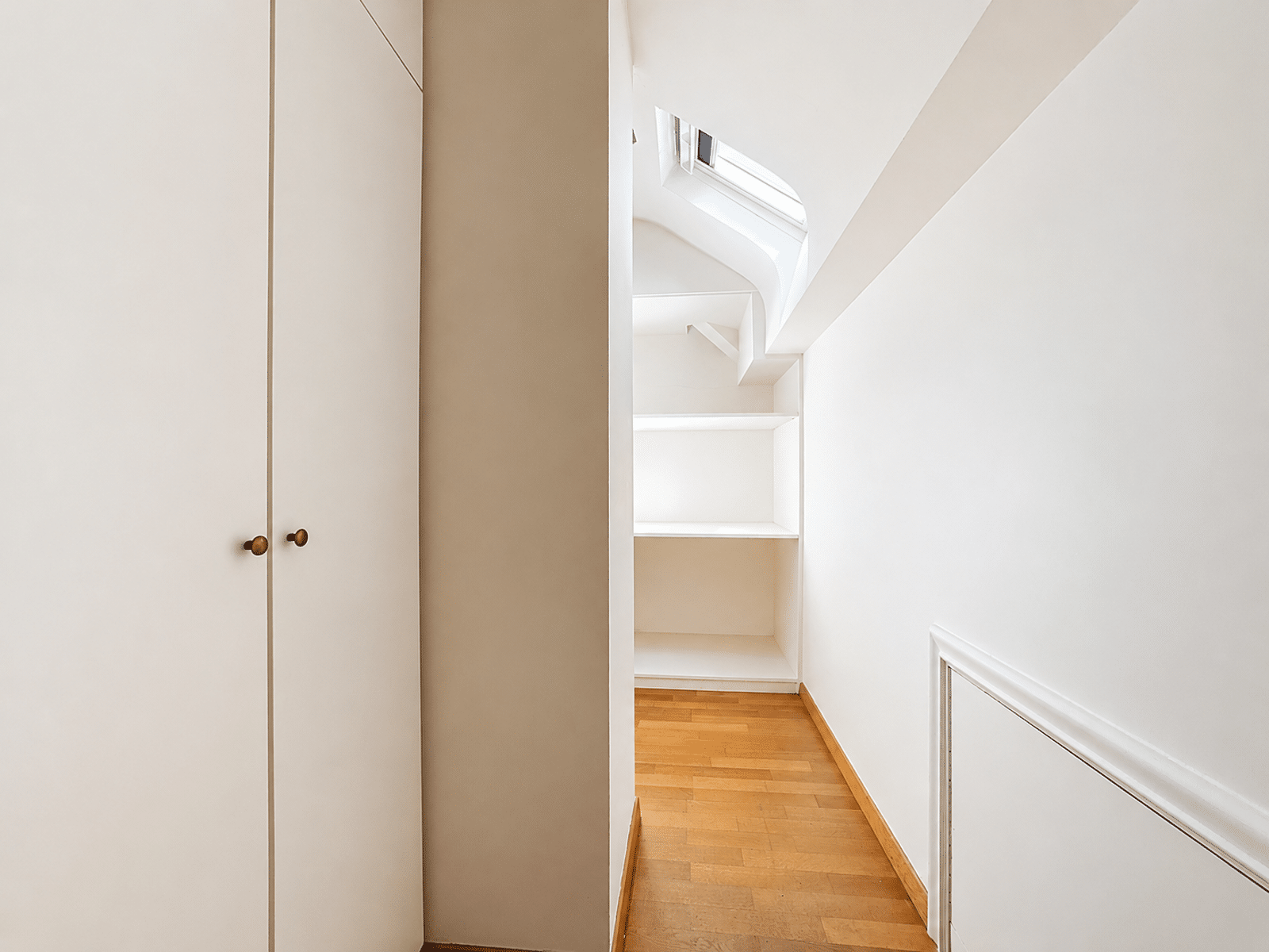 whise photo 8 Minimalist white hallway with built-in shelves at the end and a wooden floor; staircase visible to the right.