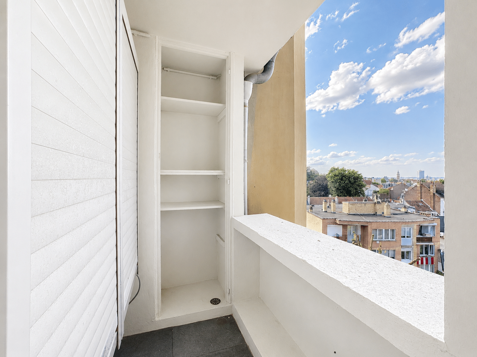 Balcon Utilitaire Avec Vue Urbaine – You Real Estate Agency Balcon utilitaire lumineux d’un appartement avec rangements et vue urbaine.