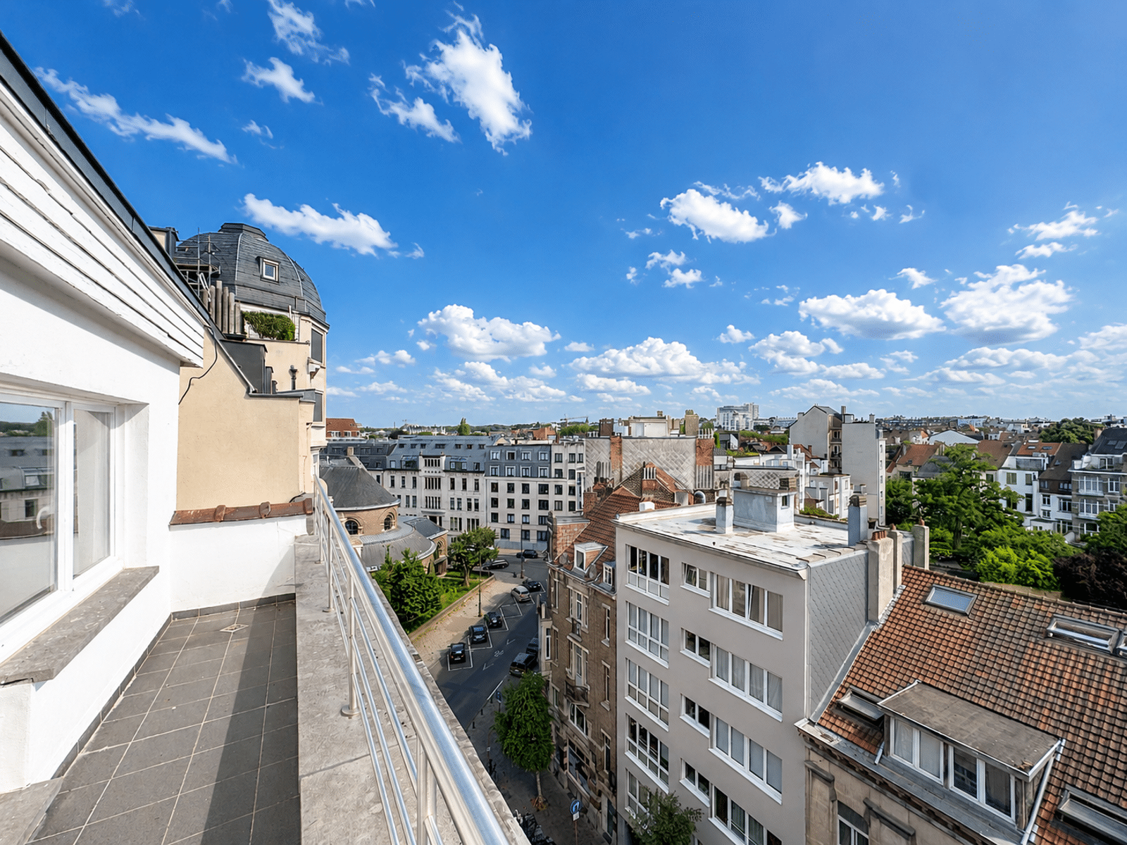 Terrasse Avec Vue Panoramique – You Real Estate Agency Terrasse d’appartement avec vue panoramique sur quartier résidentiel ensoleillé.