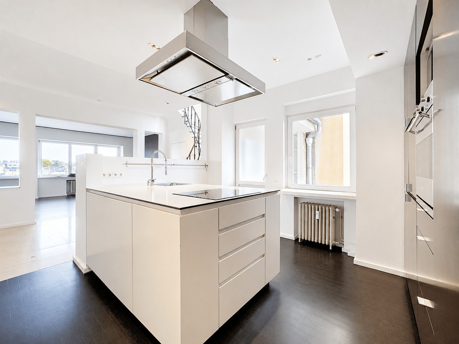 Cuisine Moderne avec Îlot Central – You Real Estate Agency Cuisine moderne ouverte avec îlot central blanc et électroménagers intégrés.