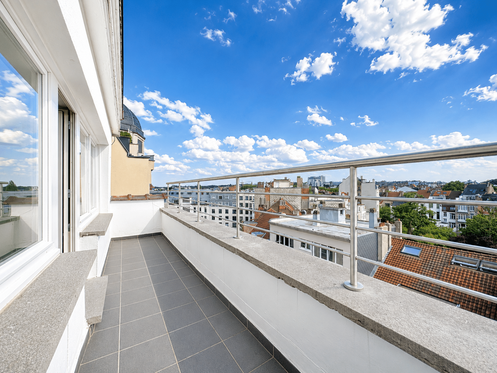 Terrasse Moderne avec Vue Urbaine – You Real Estate Agency Terrasse d’appartement moderne avec vue dégagée sur la ville.