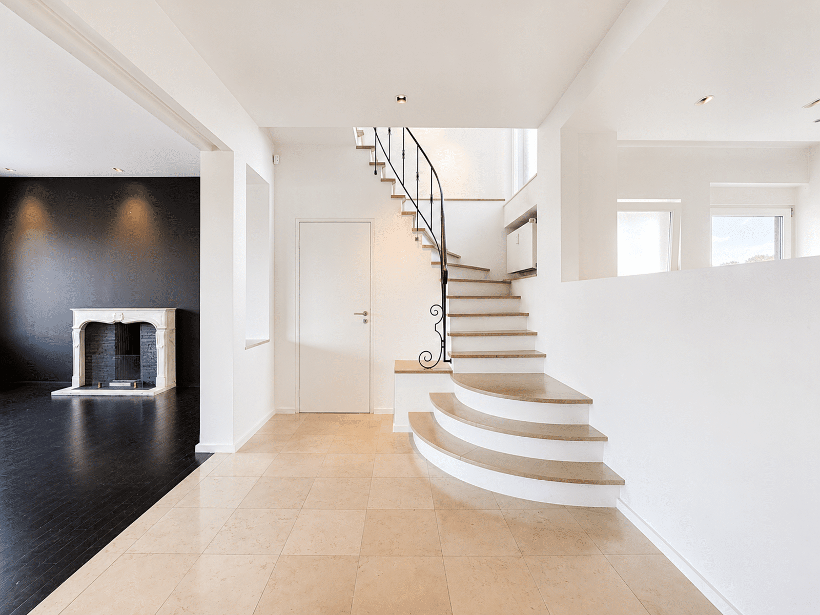 Hall Lumineux avec Escalier Design – You Real Estate Agency Hall d’entrée lumineux avec escalier design et salon avec cheminée dans une maison contemporaine.