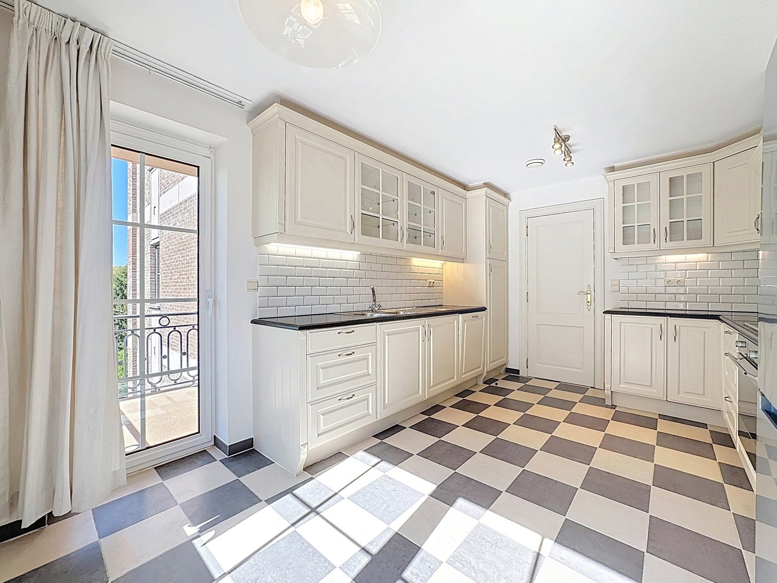 whise photo 3 Bright white kitchen with glass-front cabinets, subway tile backsplash, and a black countertop.