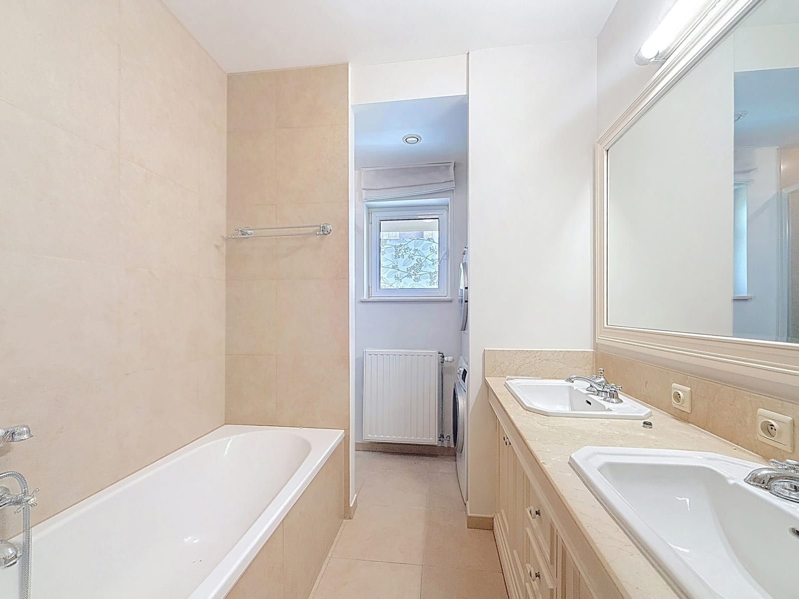whise photo 10 Bright beige-tiled bathroom with a long vanity, double sinks, and a bathtub on the left.