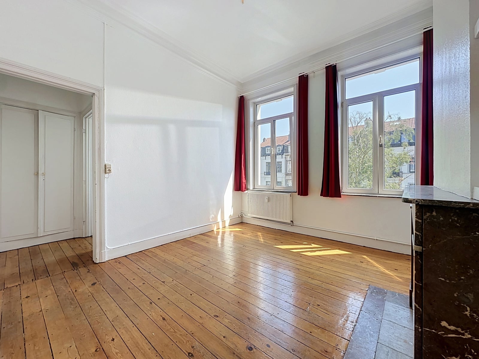 Salon Lumineux avec Parquet Ancien – You Real Estate Agency Salon lumineux d’appartement avec parquet ancien, hautes fenêtres et cheminée.