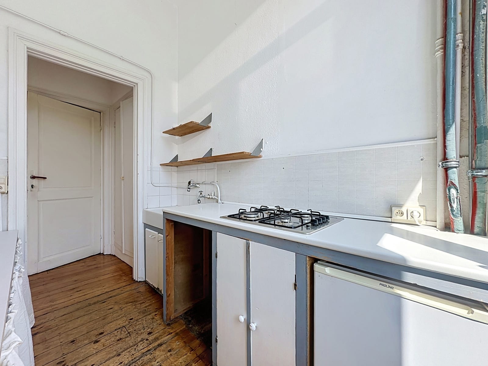 Cuisine Étroite Avec Parquet – You Real Estate Agency Cuisine étroite d’appartement avec plan de travail, évier, plaques au gaz et parquet.
