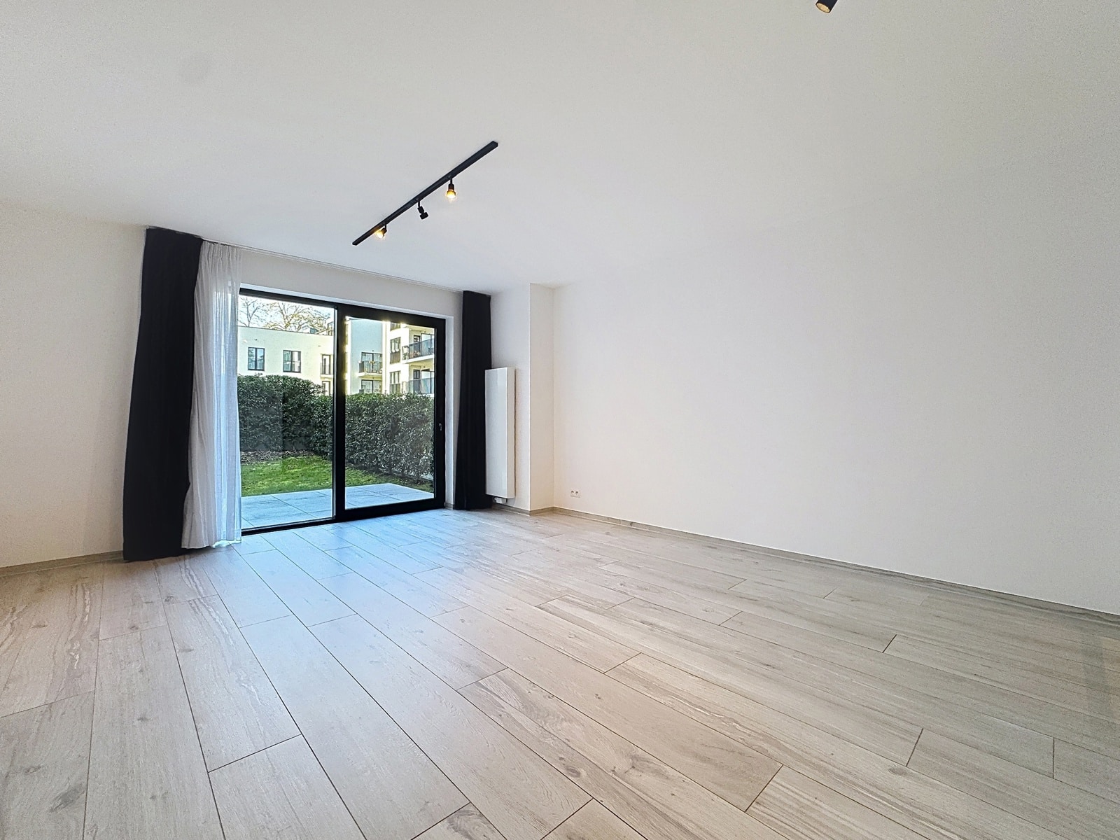 Salon Lumineux avec Terrasse – You Real Estate Agency Salon lumineux d’appartement avec terrasse, baie vitrée et parquet bois.