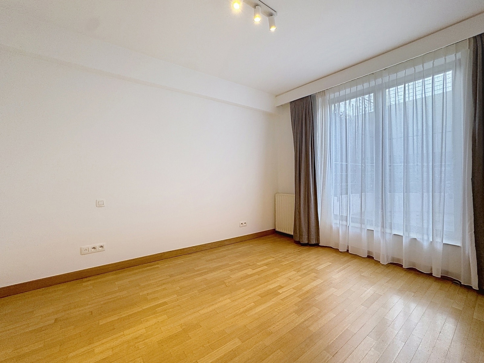 Pièce Vide Lumineuse Avec Parquet – You Real Estate Agency Pièce lumineuse d’appartement vide avec parquet, grandes fenêtres et rideaux.