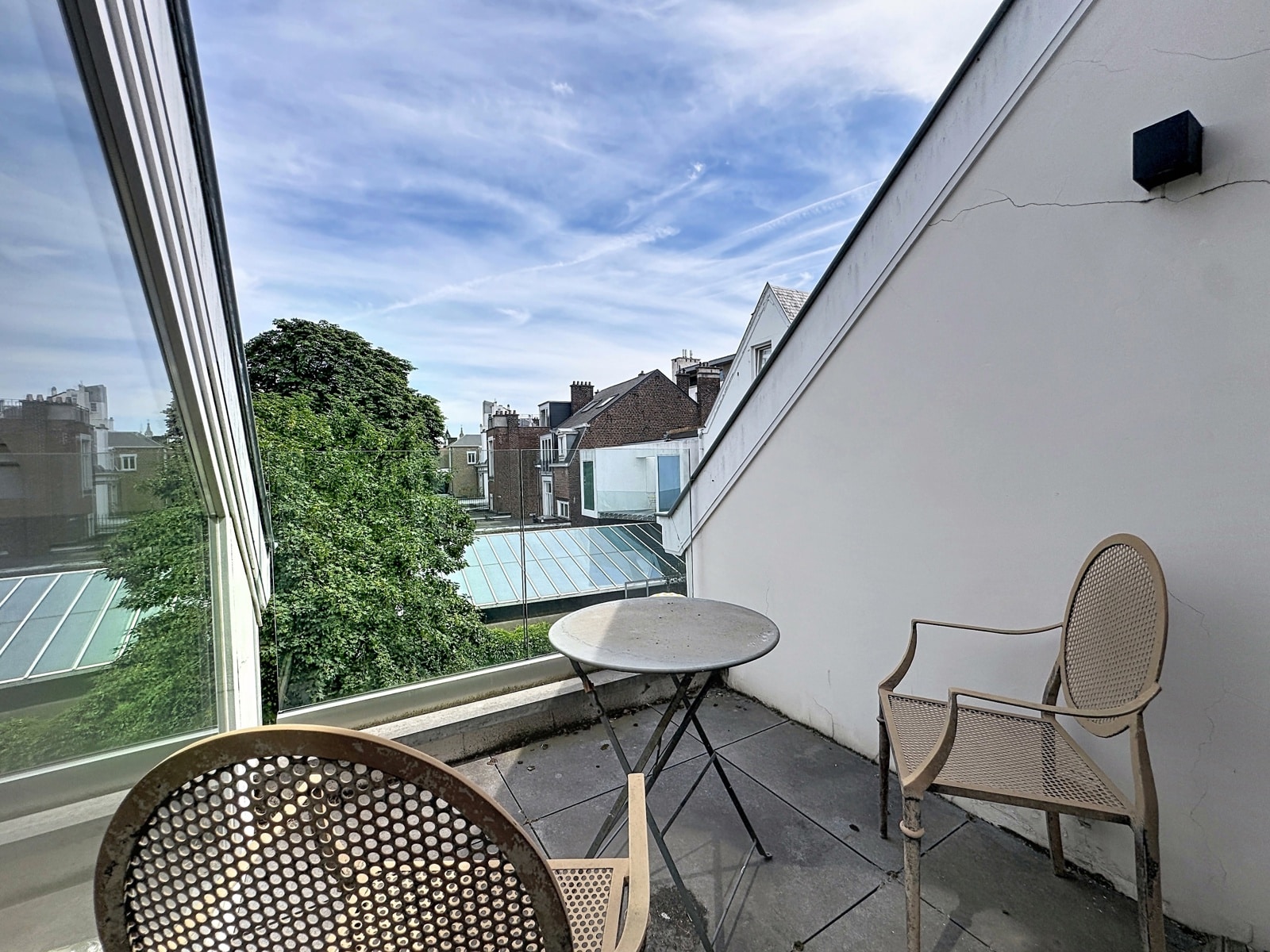 Terrasse Moderne avec Vue Urbaine – You Real Estate Agency Terrasse d’appartement moderne avec mobilier extérieur et vue urbaine dégagée.