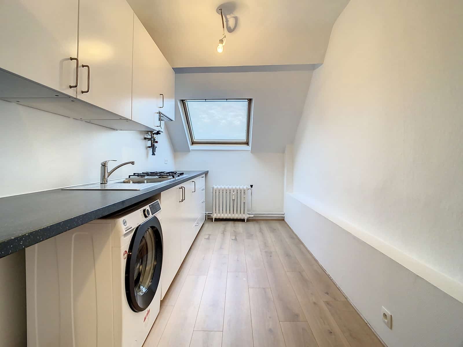 Cuisine Équipée Sous Combles – You Real Estate Agency Cuisine équipée sous combles avec puits de lumière dans un appartement rénové.