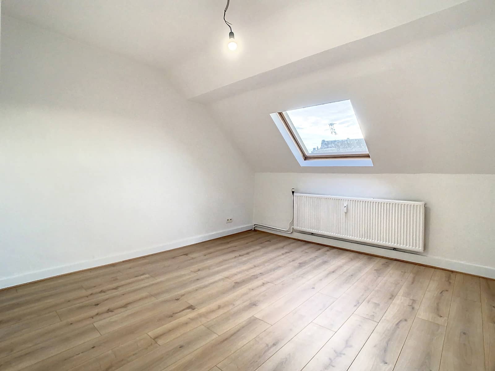 Pièce Mansardée Lumineuse avec Velux – You Real Estate Agency Pièce mansardée lumineuse avec parquet et Velux dans appartement rénové.