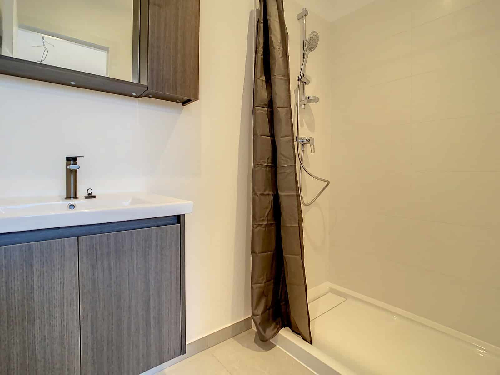 Salle de Bain Moderne – You Real Estate Agency Salle de bain moderne avec douche à l’italienne et meuble vasque en appartement.