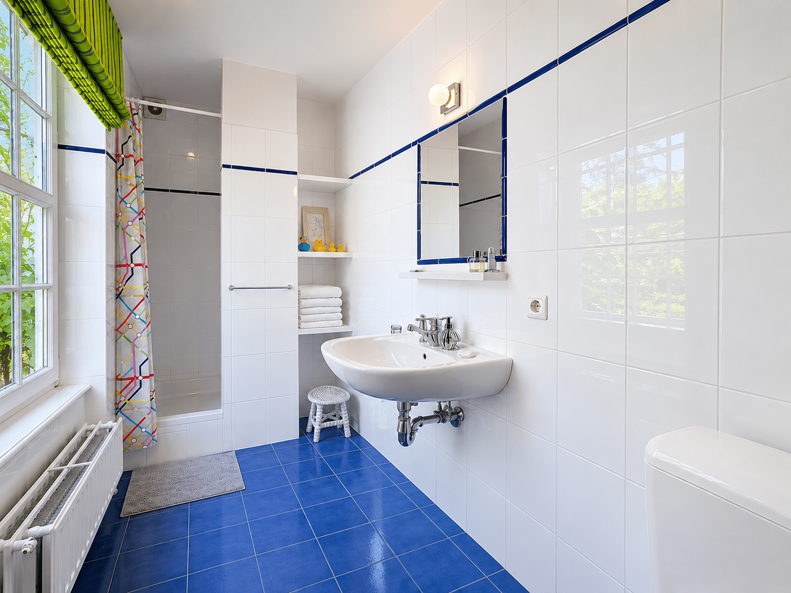 Salle de Bains Lumineuse Carrelée – You Real Estate Agency Salle de bains lumineuse aux carreaux bleus et blancs dans appartement rénové.